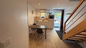 Une cuisine moderne avec un coin repas, un plancher en bois et un escalier.