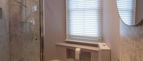 A modern bathroom with a glass-enclosed shower, a white sink, and a toilet.