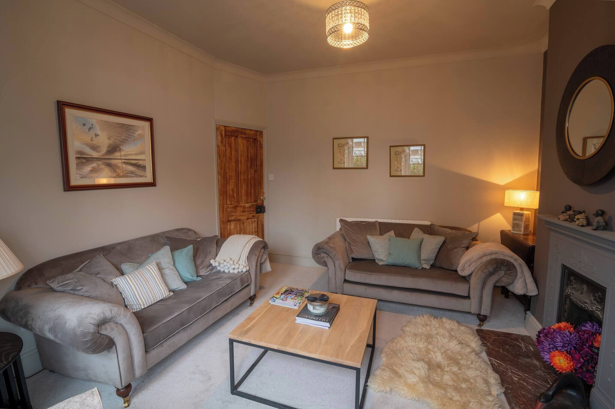 Ein Wohnzimmer mit zwei Sofas, einem Couchtisch, einem Kamin und einem gerahmten Bild an der Wand.