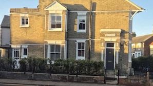 A two-story brick house with a gabled roof, a front door, and a small porch area. - Refurbished Victorian House (Colchester)