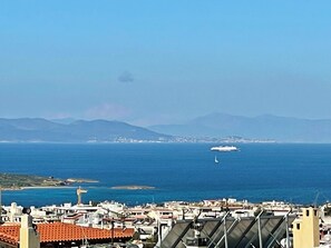 Paisagem costeira com vista para o mar, um cruzeiro e um veleiro.