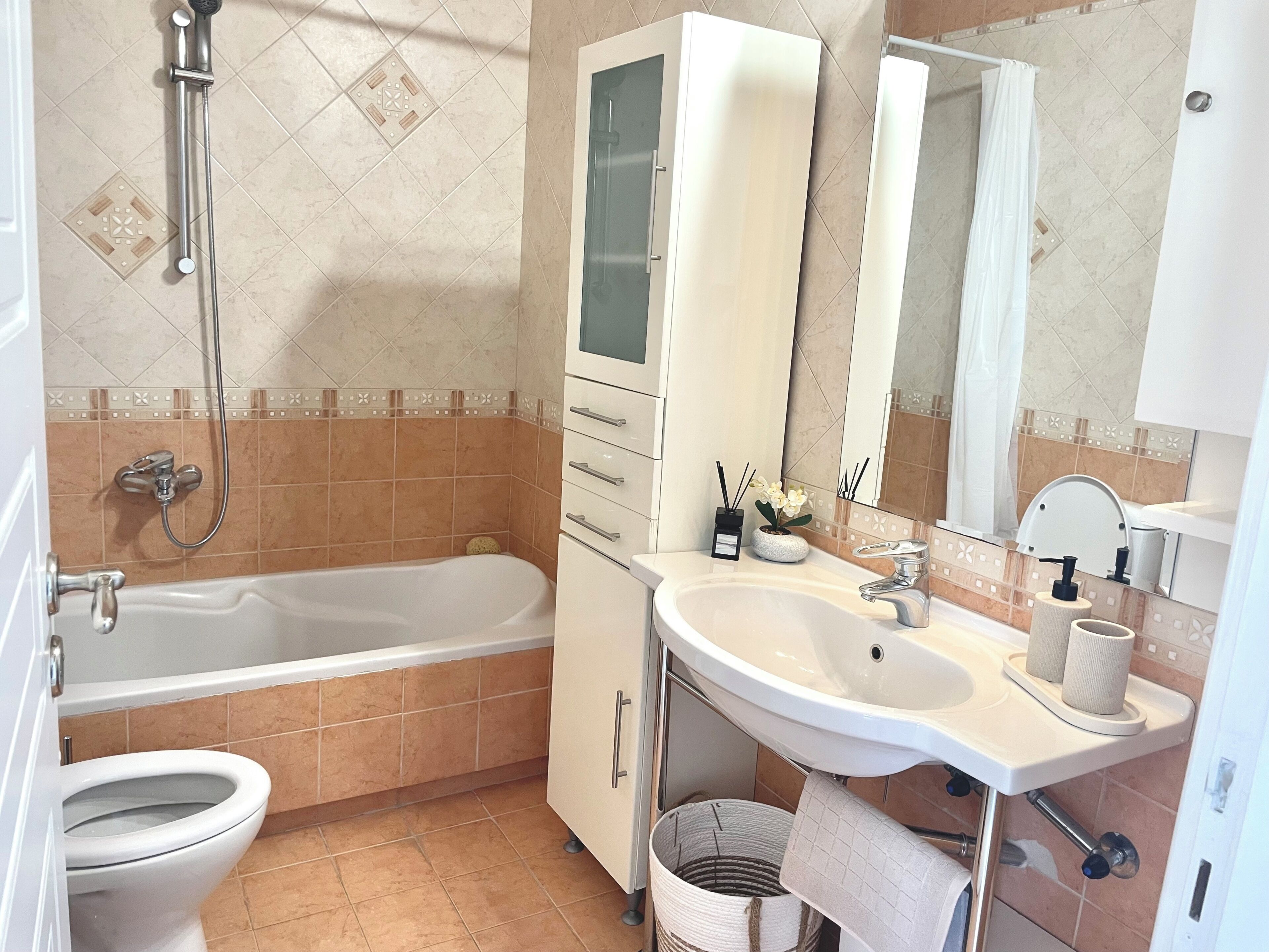 Een badkamer met een bad, toilet, wastafel en spiegel.