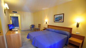 A hotel room with a large bed, a desk with a computer, two chairs, and a painting on the wall. - Hotel Olas de Almuñécar (Almuñécar)