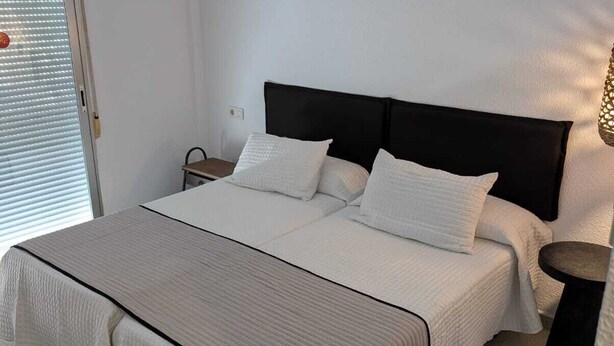 A bedroom with a large bed, a bedside table, a nightstand, and a lamp. - Hotel Olas de Almuñécar (Almuñécar)