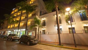 A multi-story hotel with balconies, palm trees, and street lamps. - Hotel Olas de Almuñécar (Almuñécar)