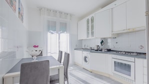 A modern kitchen with white cabinets, a washing machine, and a stove. - Bijoux in the Centre of Sanremo by Wonderful Italy (Sanremo)