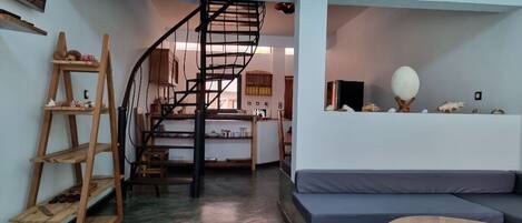 A modern interior with a spiral staircase, a wooden shelf, a sofa, and a round wooden table.