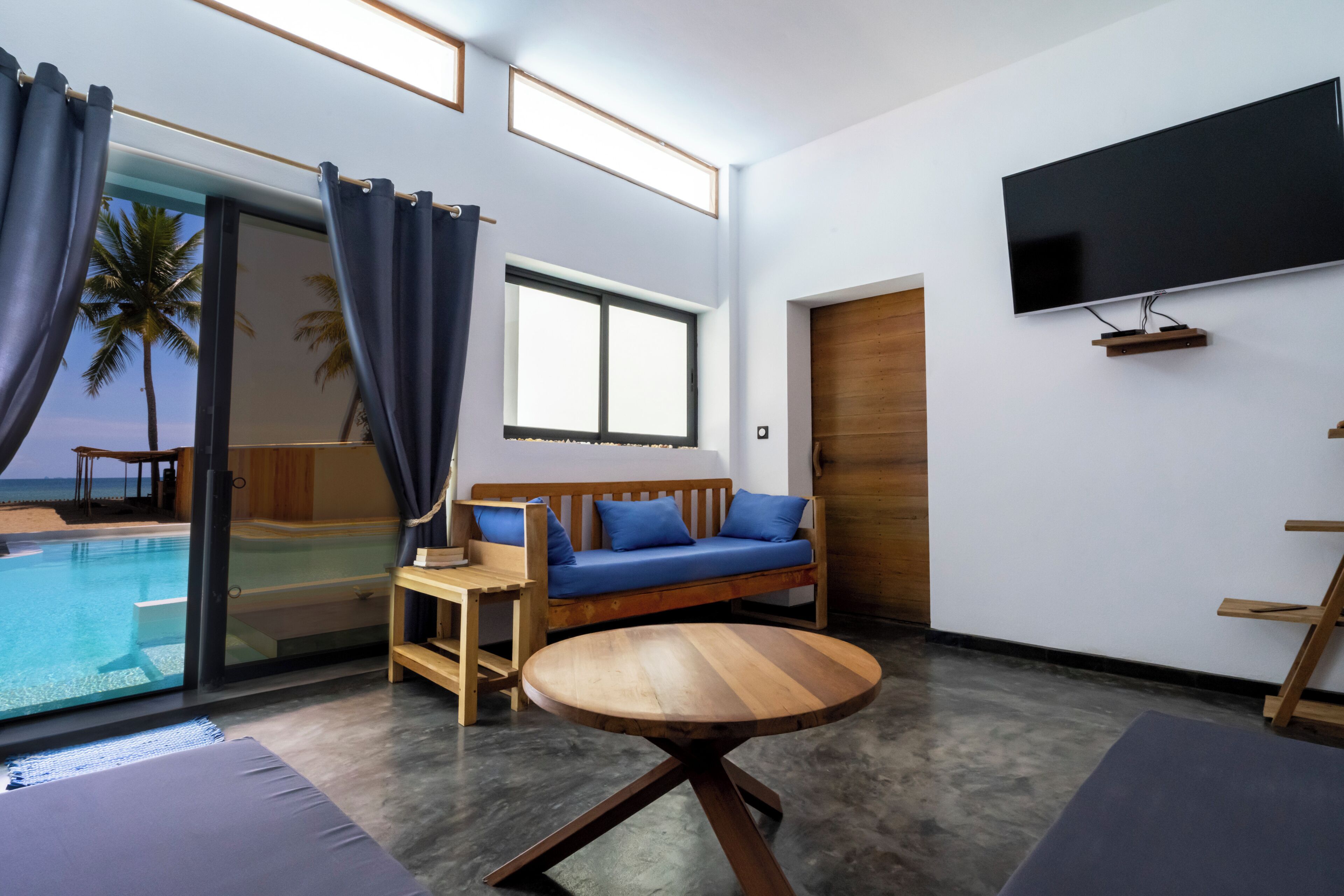 A modern room with a pool, a sofa, a TV, and a wooden table.