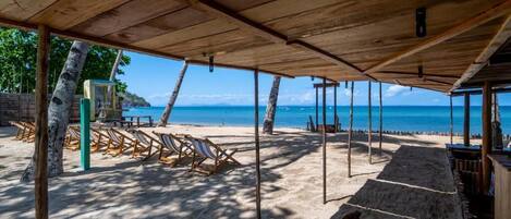 A beachside area with a wooden structure, beach chairs, and a dog.