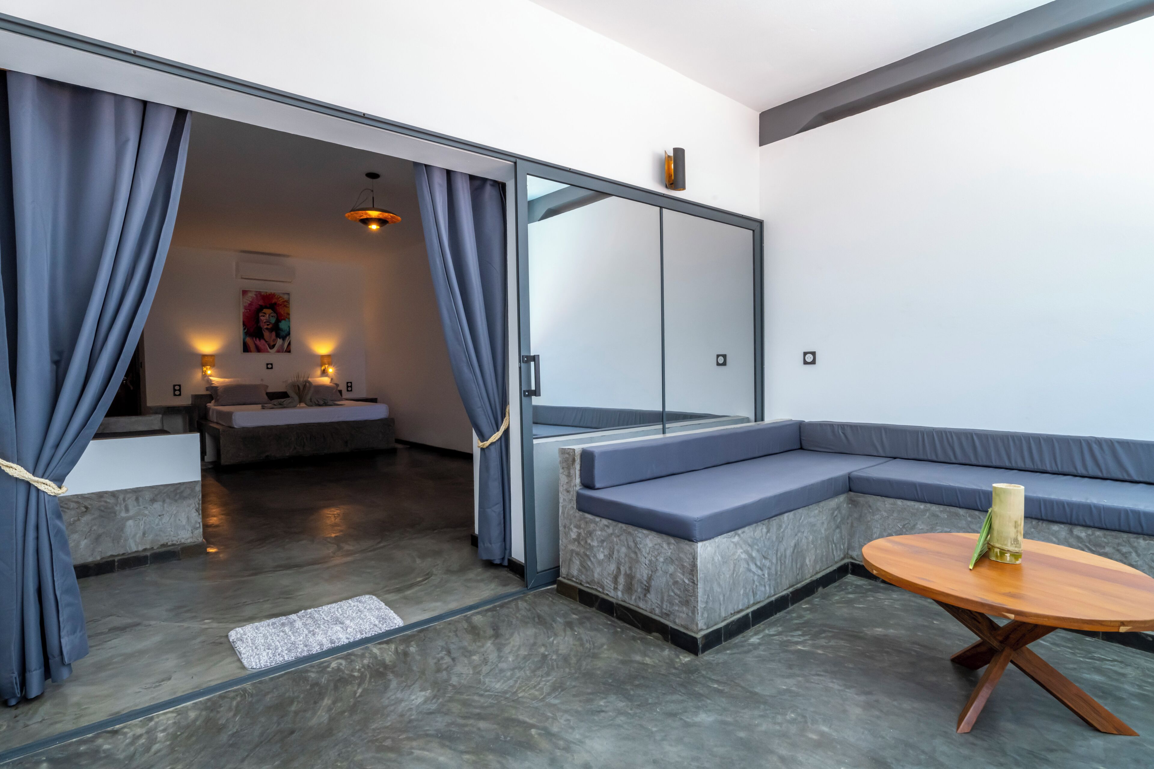 A modern interior with a sofa, a round wooden table, and a sliding door leading to another room.