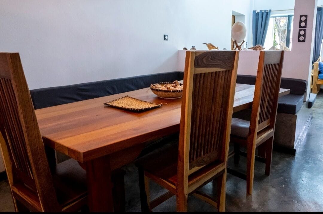 A wooden dining table with chairs, a woven placemat, and a bowl of bread.