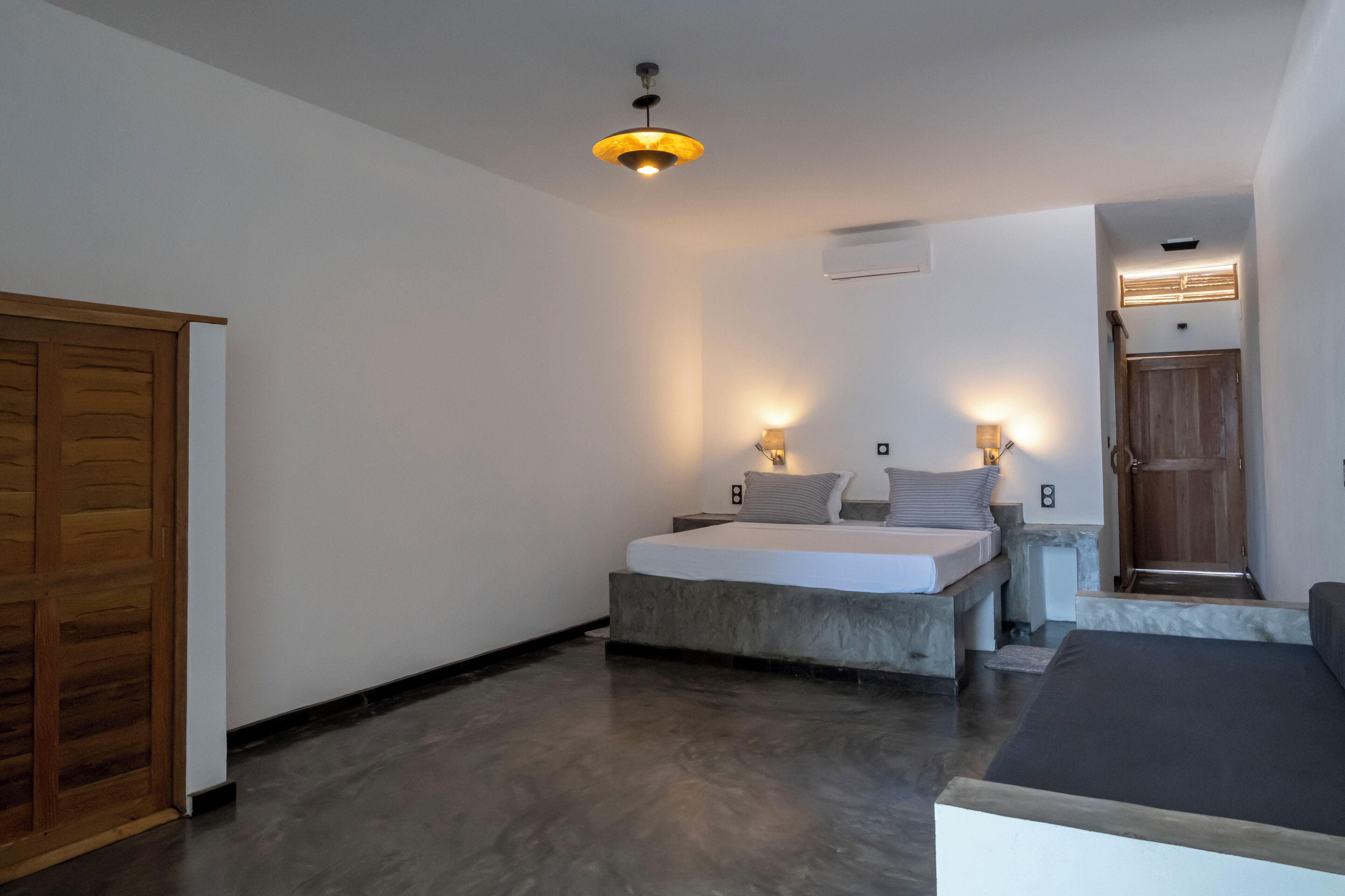 A bedroom with a bed, bedside tables, a wardrobe, and a door.