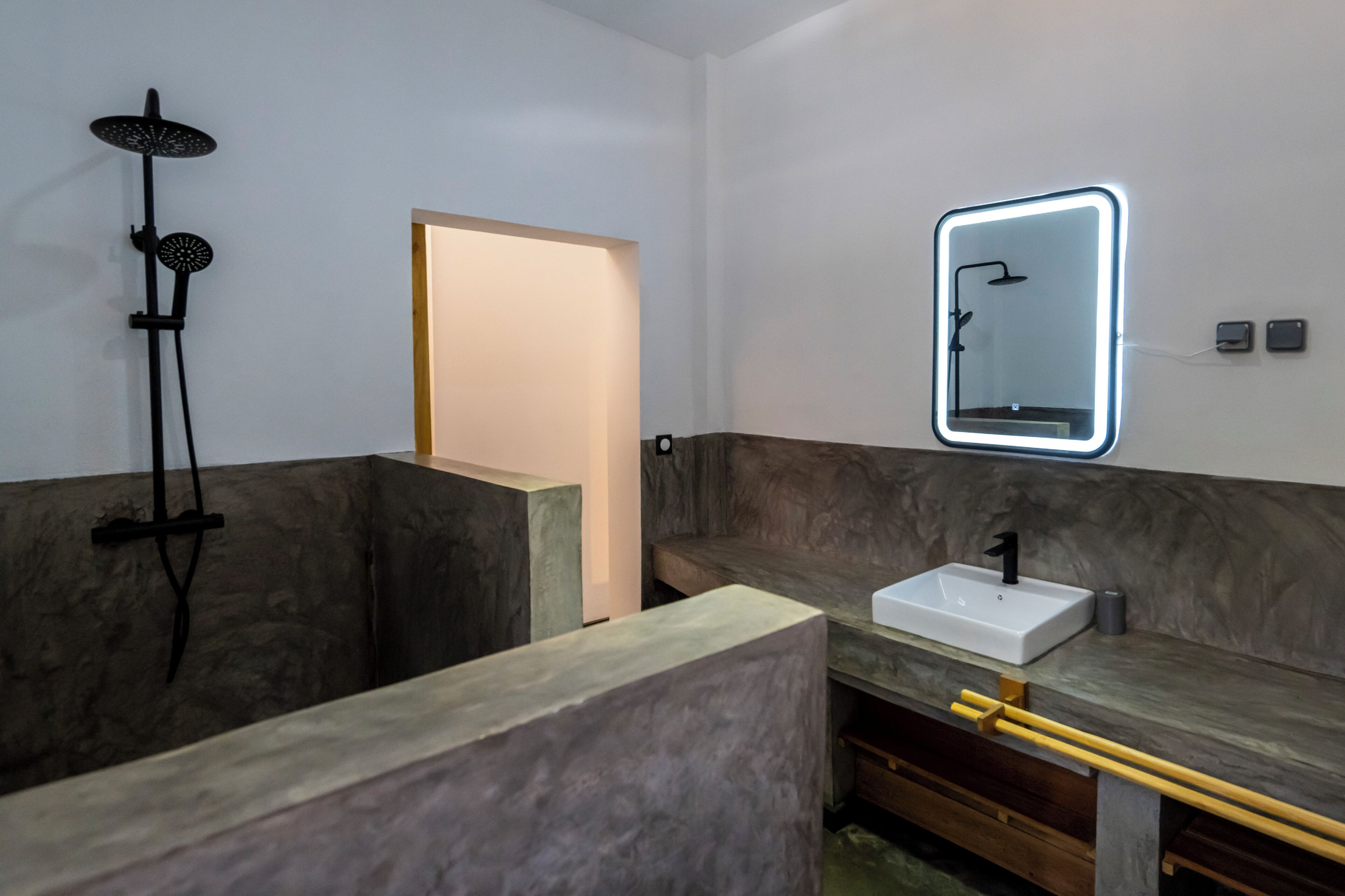 A modern bathroom with a shower, a sink, and a mirror with a neon light.