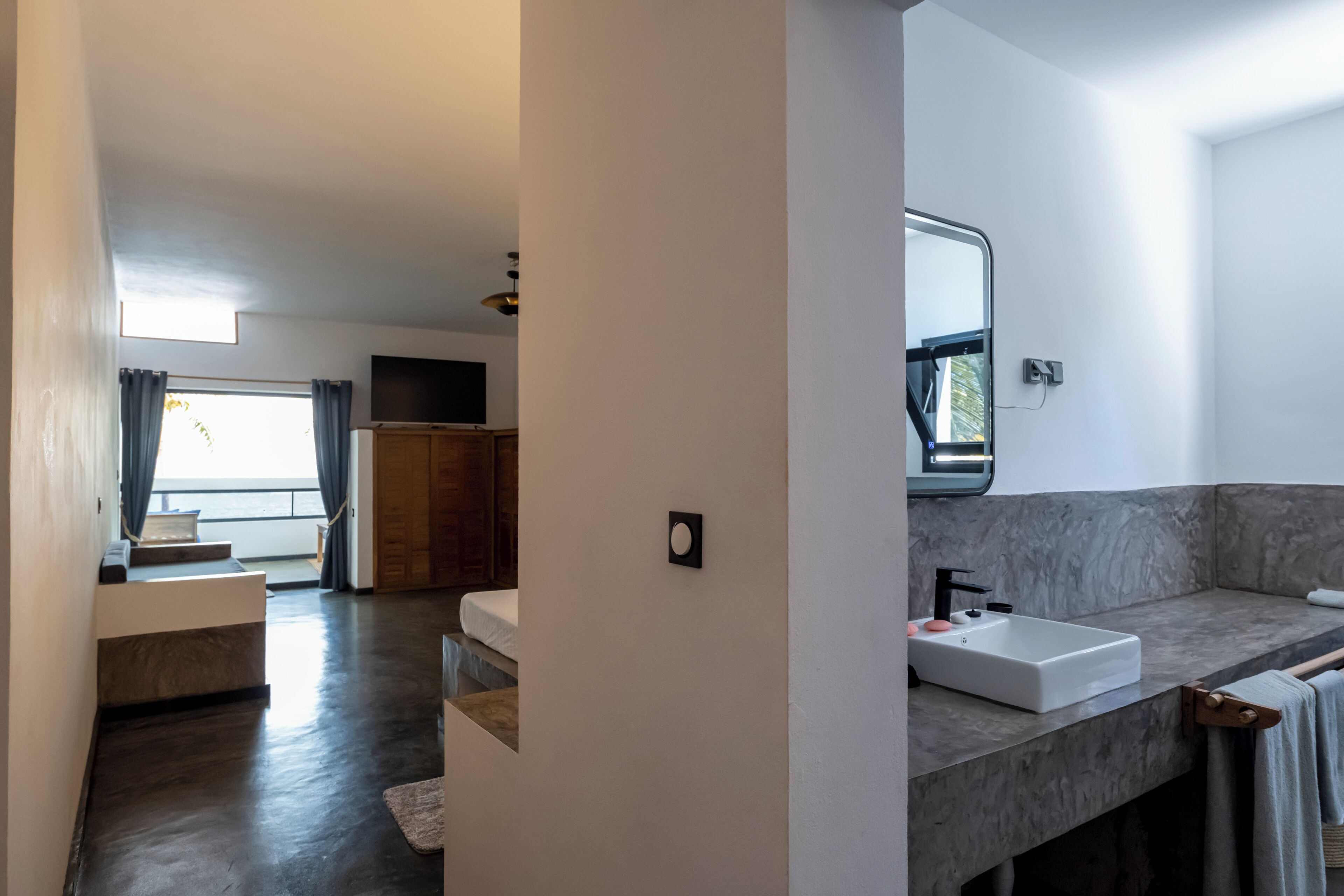 A modern bathroom with a large sink, mirror, and towel rack.
