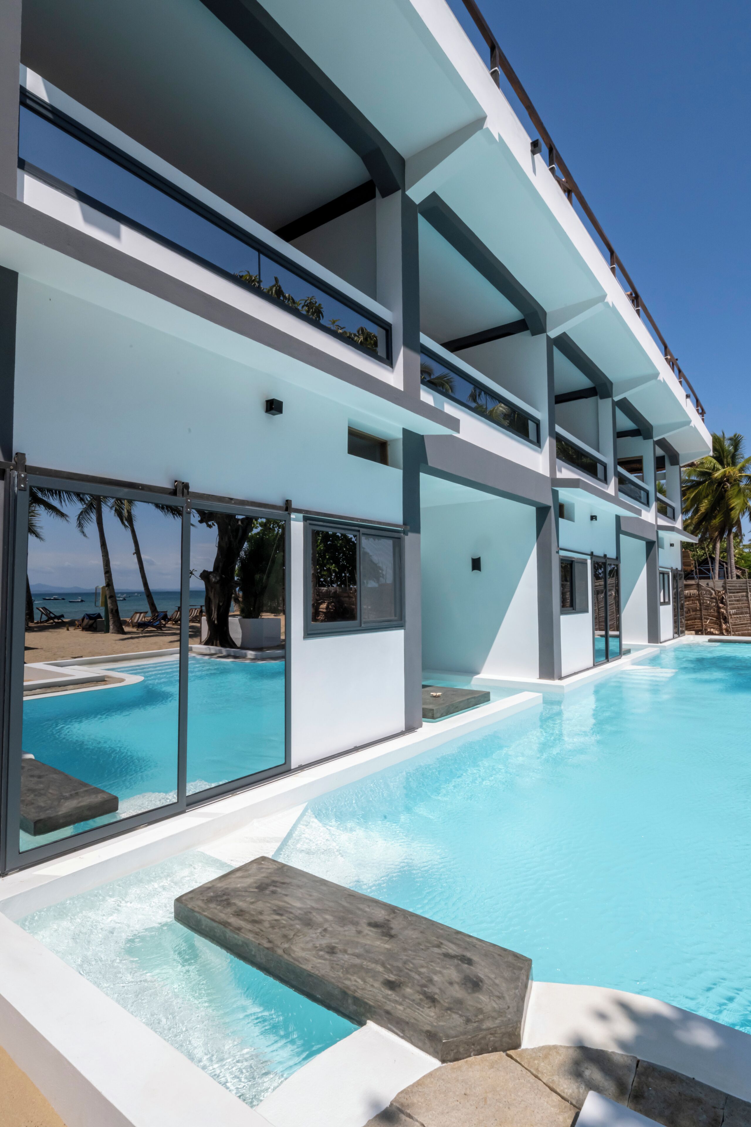Un hotel moderno con piscina, balcones y vistas a la playa.