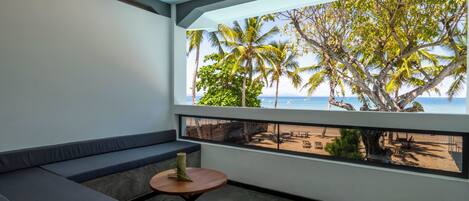 Un balcón con vista a palmeras y la playa.