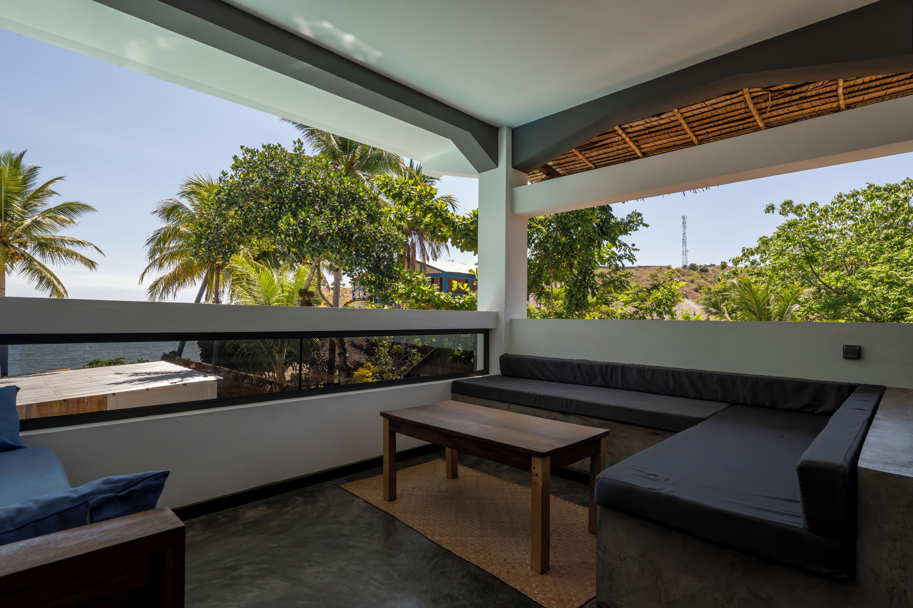 A modern outdoor seating area with a view of the sea and greenery.