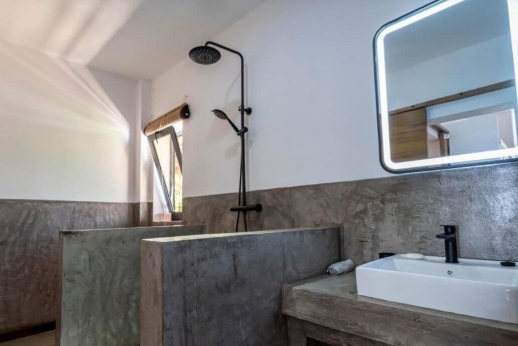 Un baño con ducha, lavamanos y espejo.