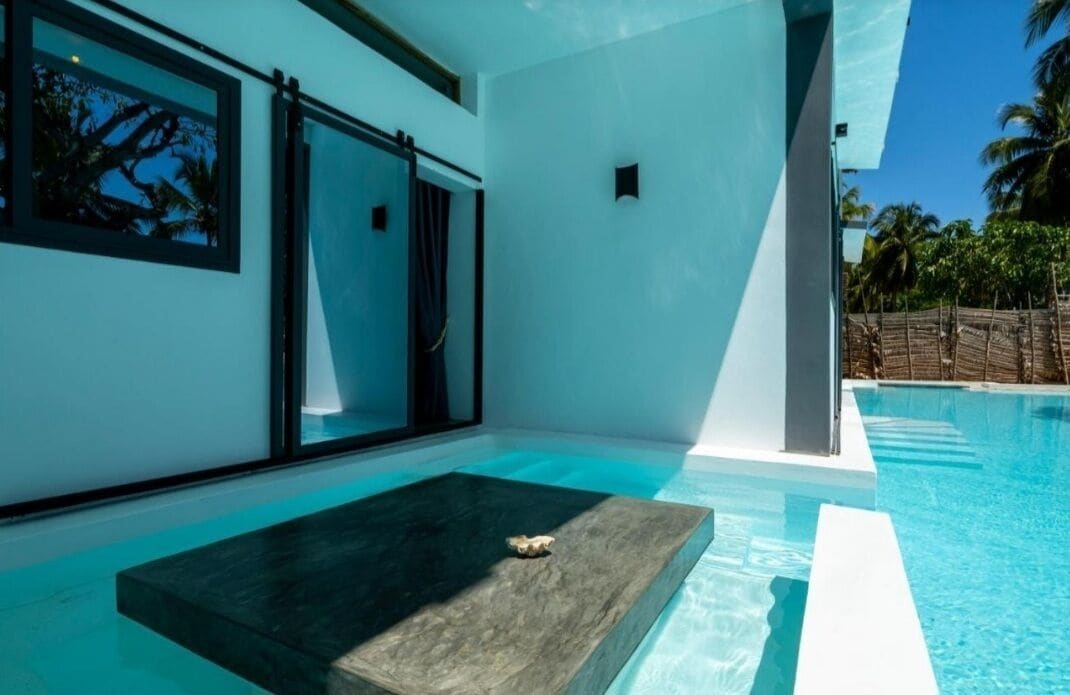 Un área de piscina moderna con diseño minimalista, un banco de piedra y vistas despejadas del paisaje circundante.