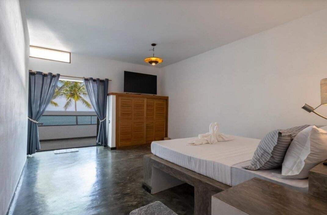 Un dormitorio con cama, un armario de madera, un televisor y una ventana con cortinas.