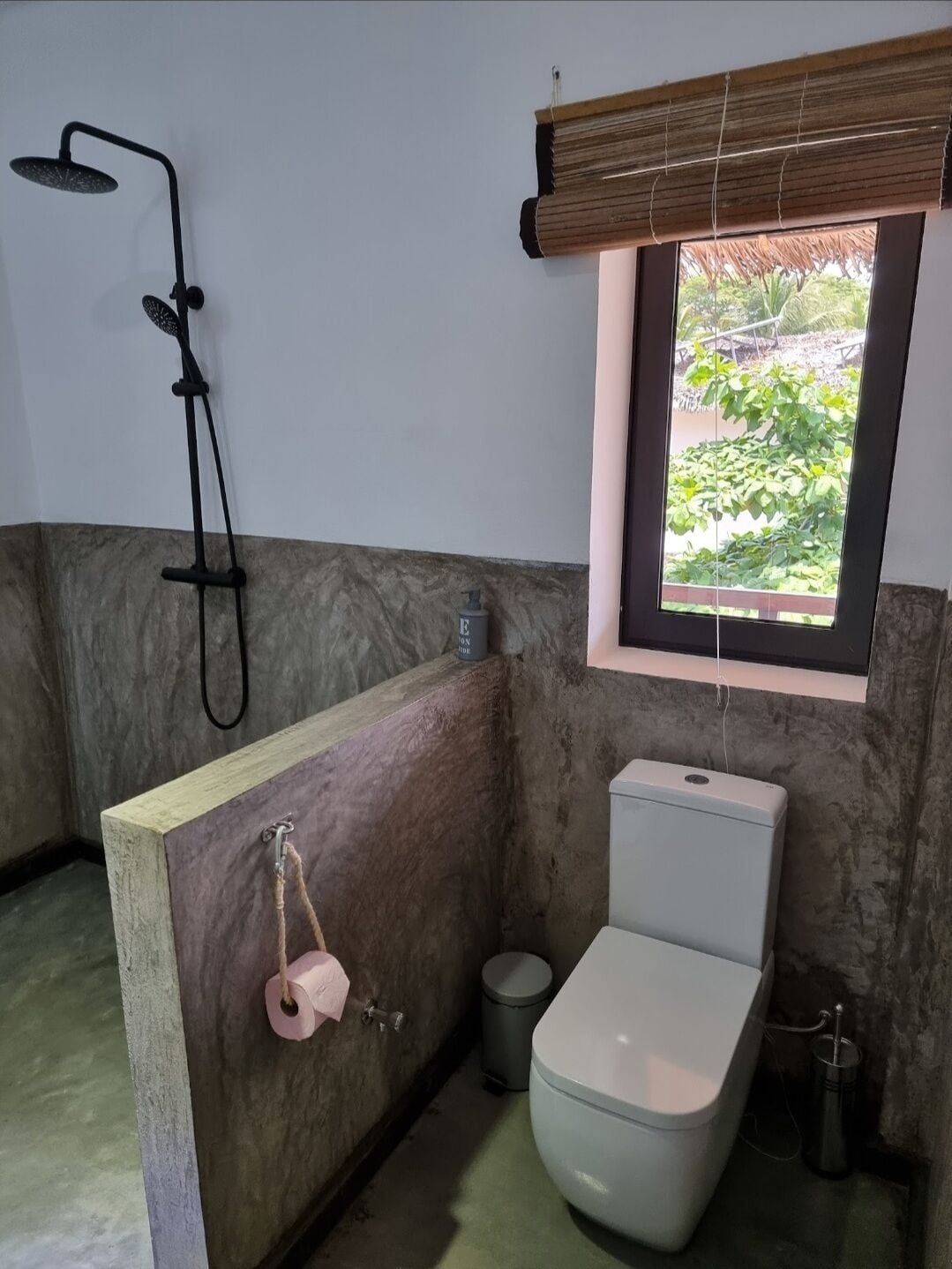 Ein Badezimmer mit Dusche, Toilette und Fenster.