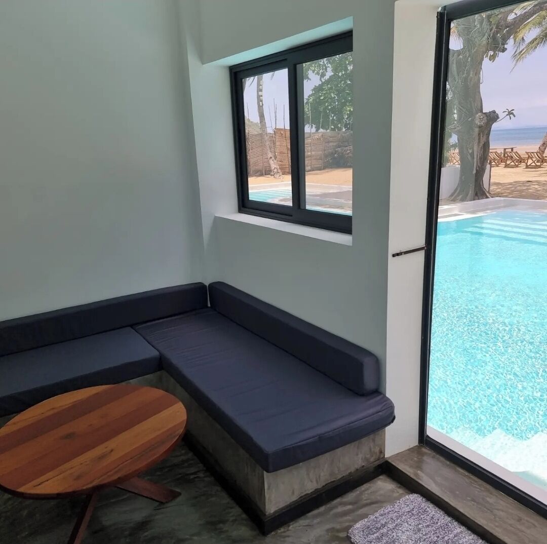 A room with a built-in seating area, a window overlooking a pool, and a wooden table.
