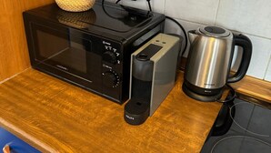 A kitchen with a black microwave, a coffee maker, and a kettle on the counter. - Cool Duplex With Terrace Near Florenc (Prague)