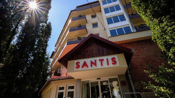 Ein Gebäude mit einem Schild mit der Aufschrift 'SANTIS' und einer Treppe, die zum Eingang führt.