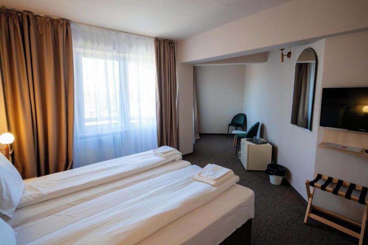 A hotel room with two beds, a TV, a desk, a chair, and a small table.