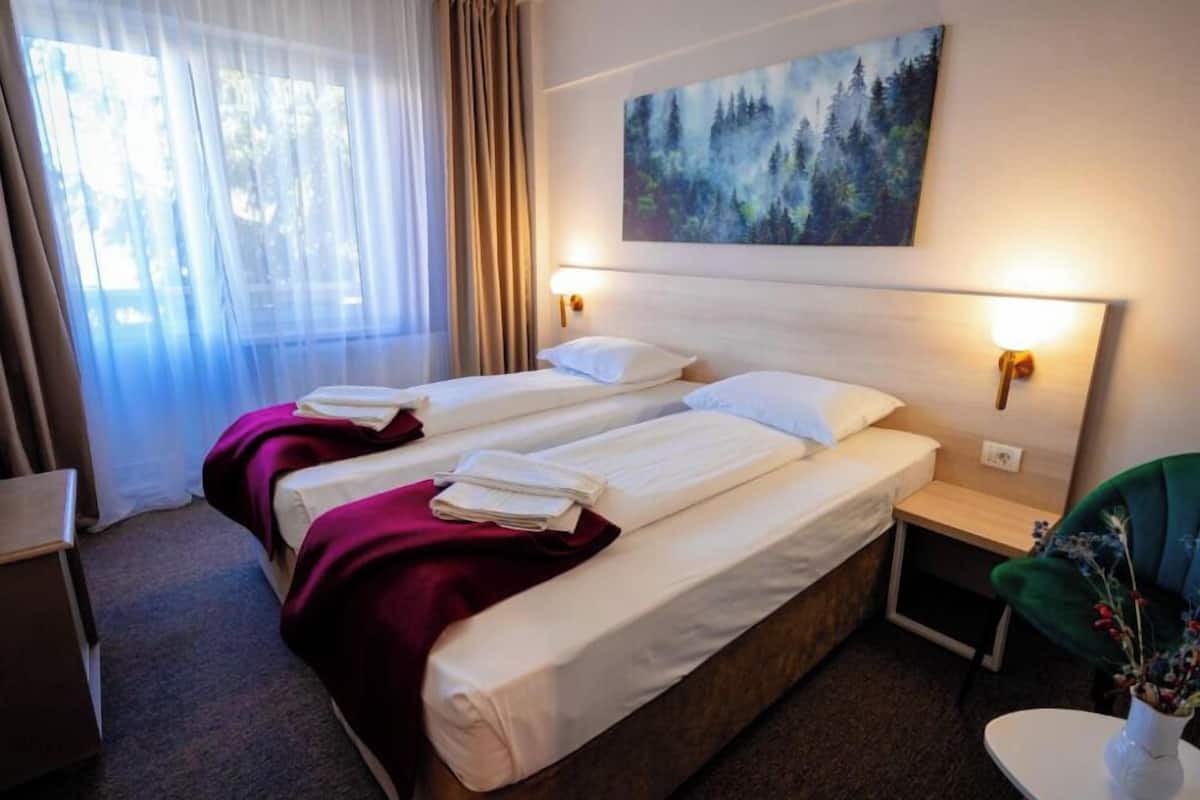Habitación de hotel con dos camas, un cuadro en la pared, un escritorio y una silla.