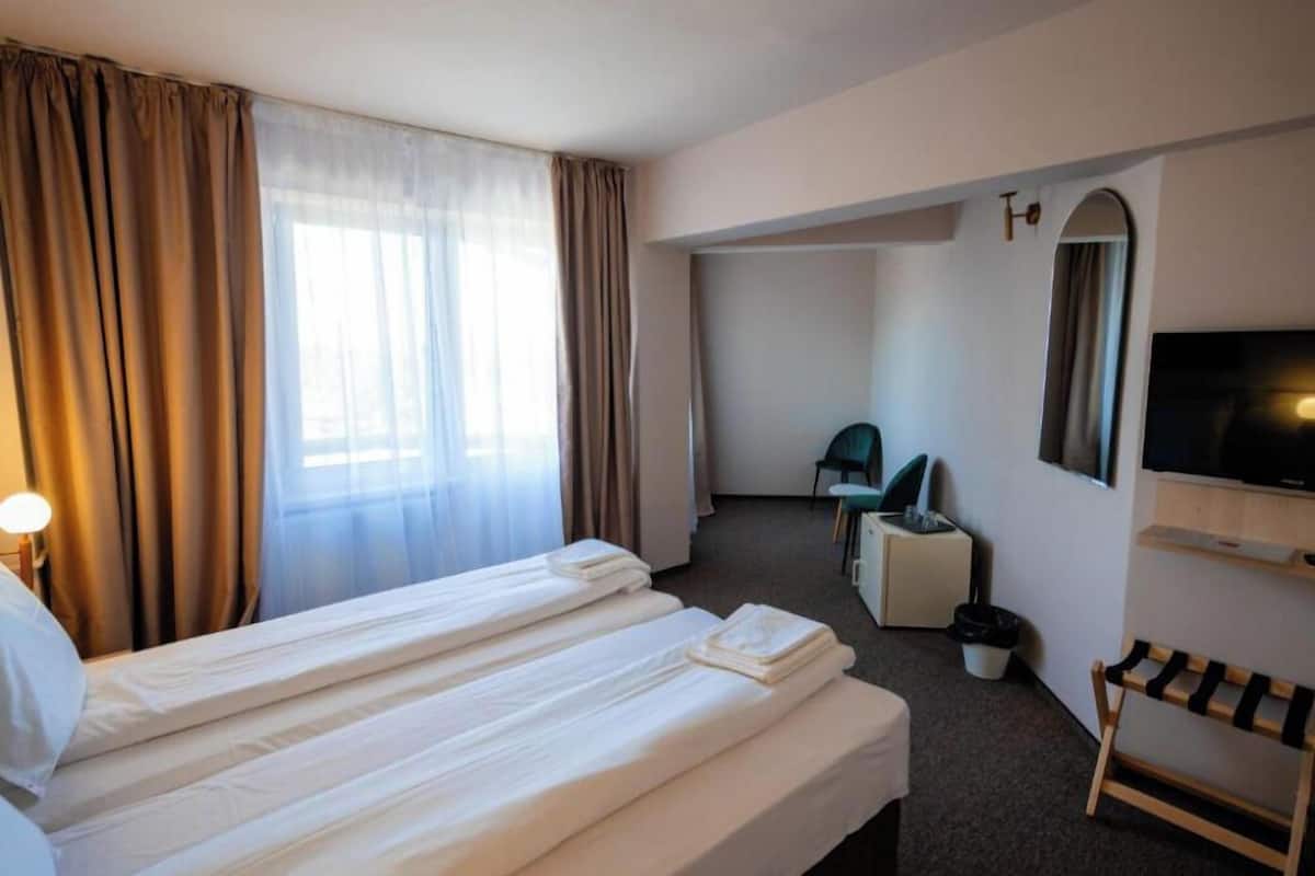 Habitación de hotel con dos camas, televisión, escritorio, silla y una mesita.