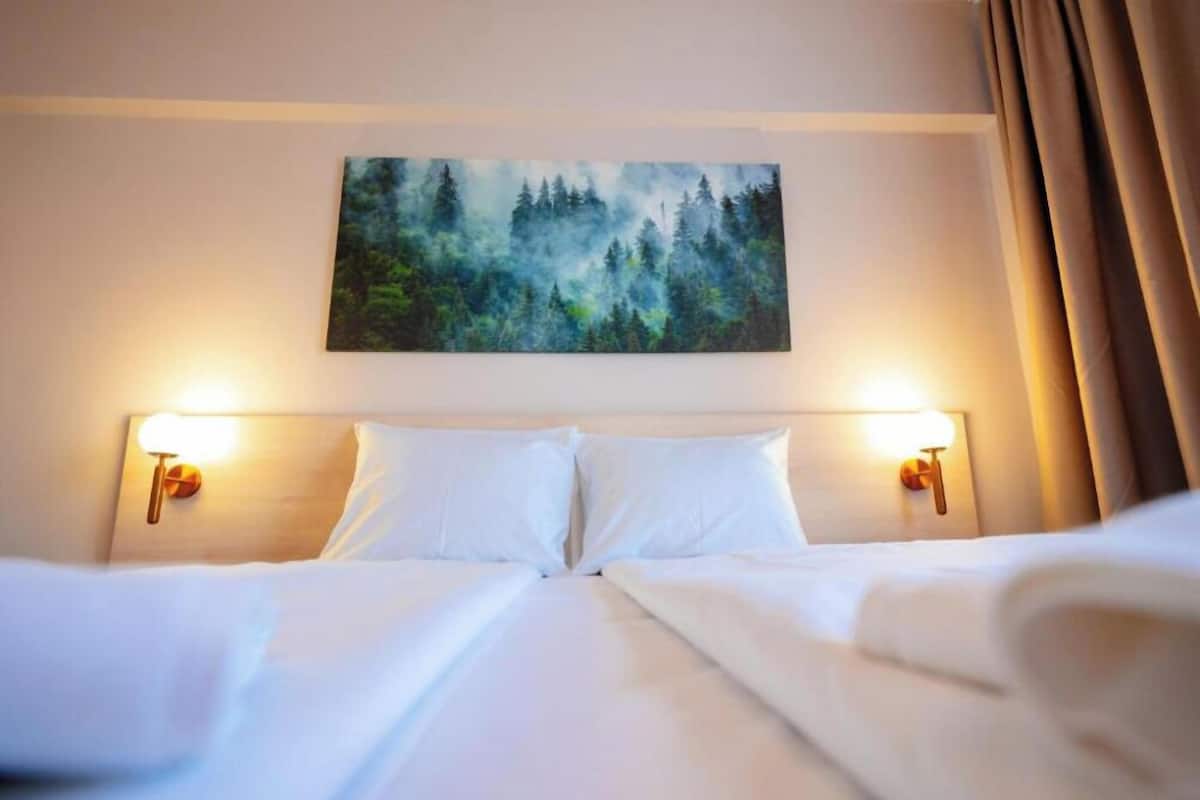 Una habitación de hotel con una cama, dos lámparas de noche y un cuadro sobre la cama.