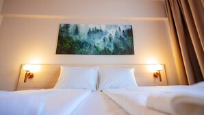 Ein Hotelzimmer mit einem großen Bett, zwei Nachttischlampen und einem Wandbild mit Waldmotiv.