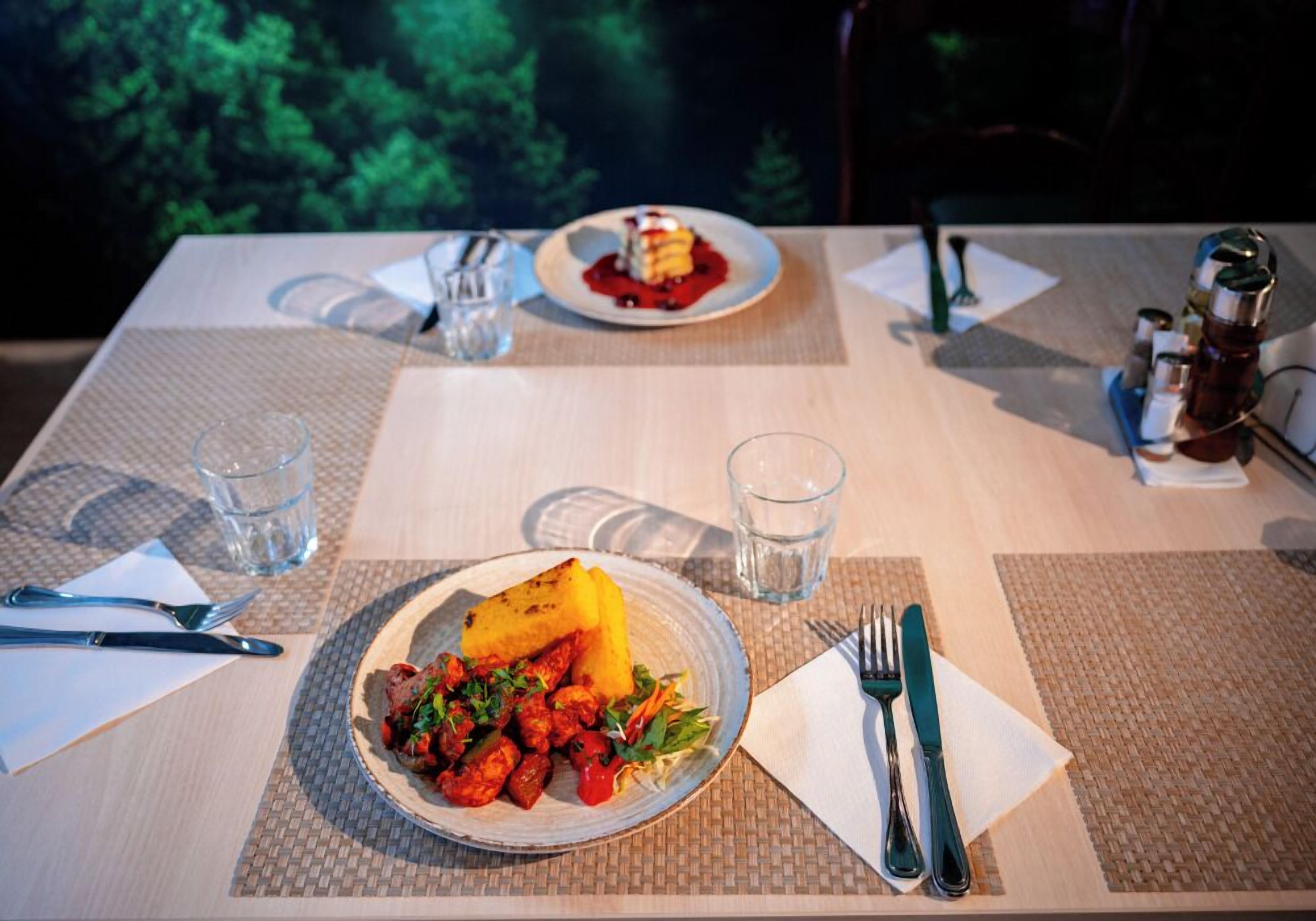 A dining table with plates of food, cutlery, and glasses.