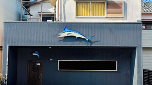 A modern two-story house with a garage, a blue shark decoration on the garage door, and a clear blue sky.