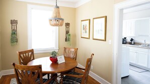 A dining area with a round wooden table, four chairs, a hanging light fixture, and two framed botanical prints on the wall. - Close to what brought you here, quiet when you get back. A comfortable 2BR where work trips, longer stays, couples, and pets can settle into Montgomery without living like travelers. (Montgomery)