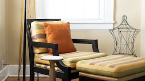 A room with a wooden floor, a chair with striped cushions, a small table, a floor lamp, and a decorative metal piece. - Close to what brought you here, quiet when you get back. A comfortable 2BR where work trips, longer stays, couples, and pets can settle into Montgomery without living like travelers. (Montgomery)