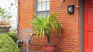 A red brick building with a red door, a potted plant, and a metal chair outside. - Close to what brought you here, quiet when you get back. A comfortable 2BR where work trips, longer stays, couples, and pets can settle into Montgomery without living like travelers. (Montgomery)