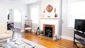 A living room with a fireplace, a television, and a dining area visible through an archway. - A surprisingly roomy, quiet Montgomery home base for families, pet travelers, and longer stays—minutes from downtown and Maxwell, with space to actually settle in. (Montgomery)
