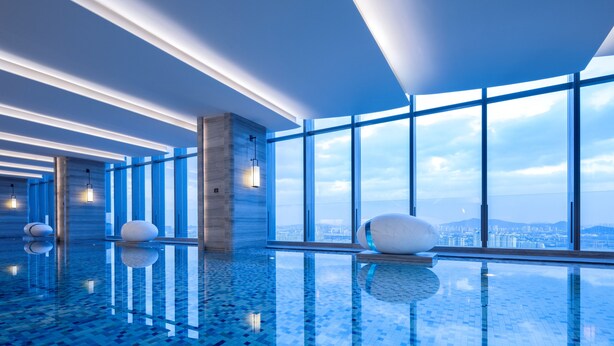 A modern indoor swimming pool with a clear view of the city skyline through large windows. - Jinmao Grandee Hotel Jiangyin Chengfa (Wuxi)