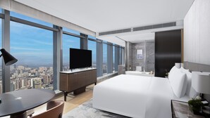 A modern hotel room with a large bed, a desk with a flat-screen TV, a dining area, and a bathroom. - Jinmao Grandee Hotel Jiangyin Chengfa (Wuxi)