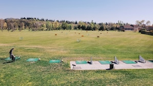 A large open field with a building in the background, green exercise mats, and a person in the foreground. - Locanda Golf Musella (San Martino Buon Albergo)