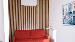 A red sofa, a white coffee table, and a striped wall. - Locanda Golf Musella (San Martino Buon Albergo)