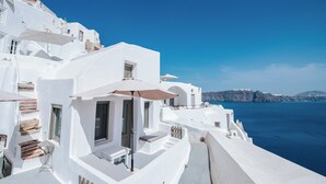 Un edifici blanc amb un balcó, una taula i una ombreig.