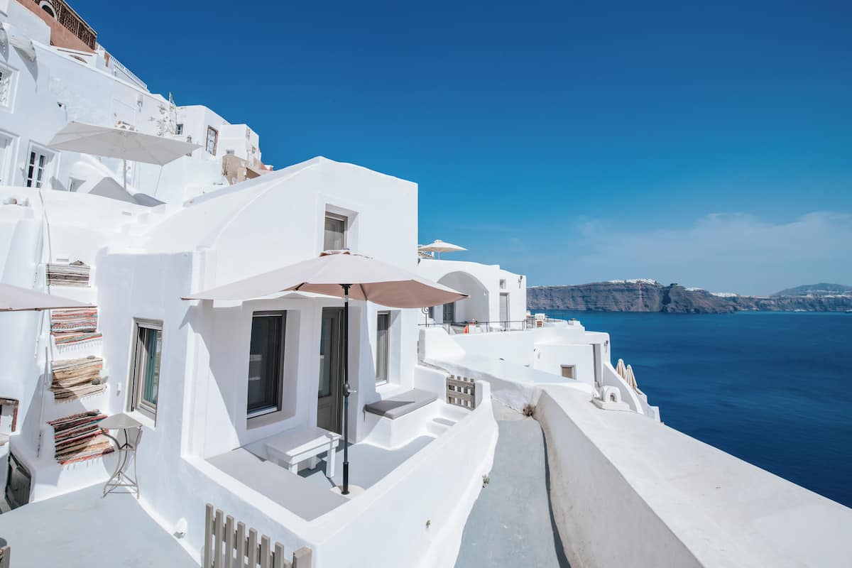 A white building with a balcony, a table, and an umbrella.