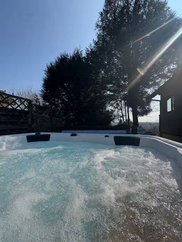 Un jacuzzi con vista a árboles y un cielo despejado.