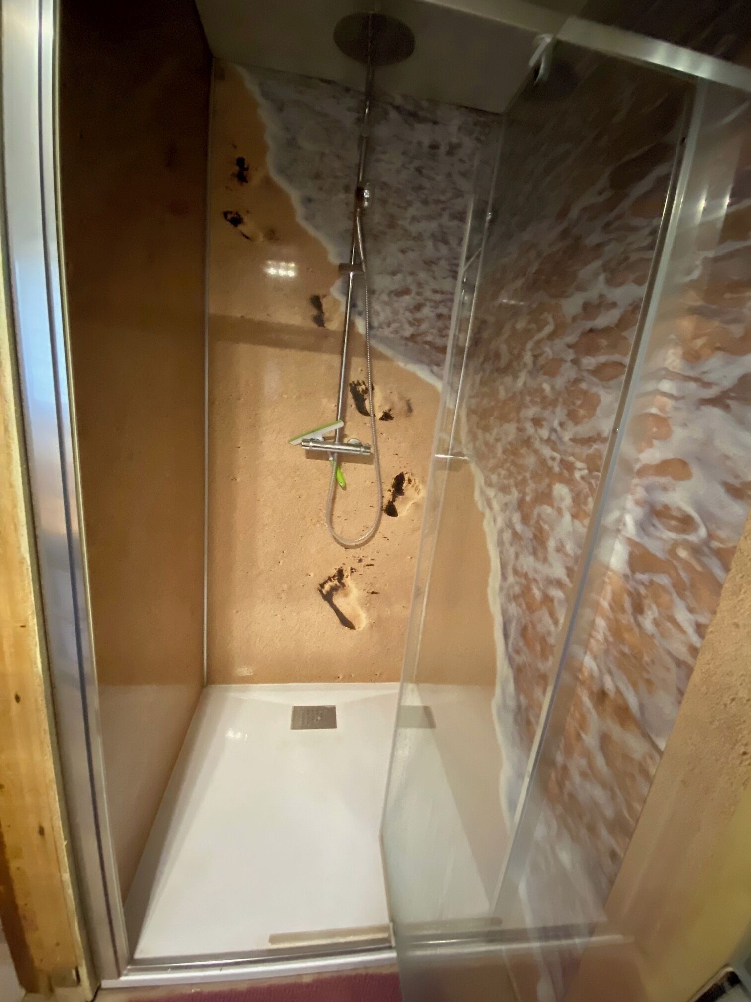 Une douche entièrementClose avec des parois en verre et un décor mural imitant le marbre.