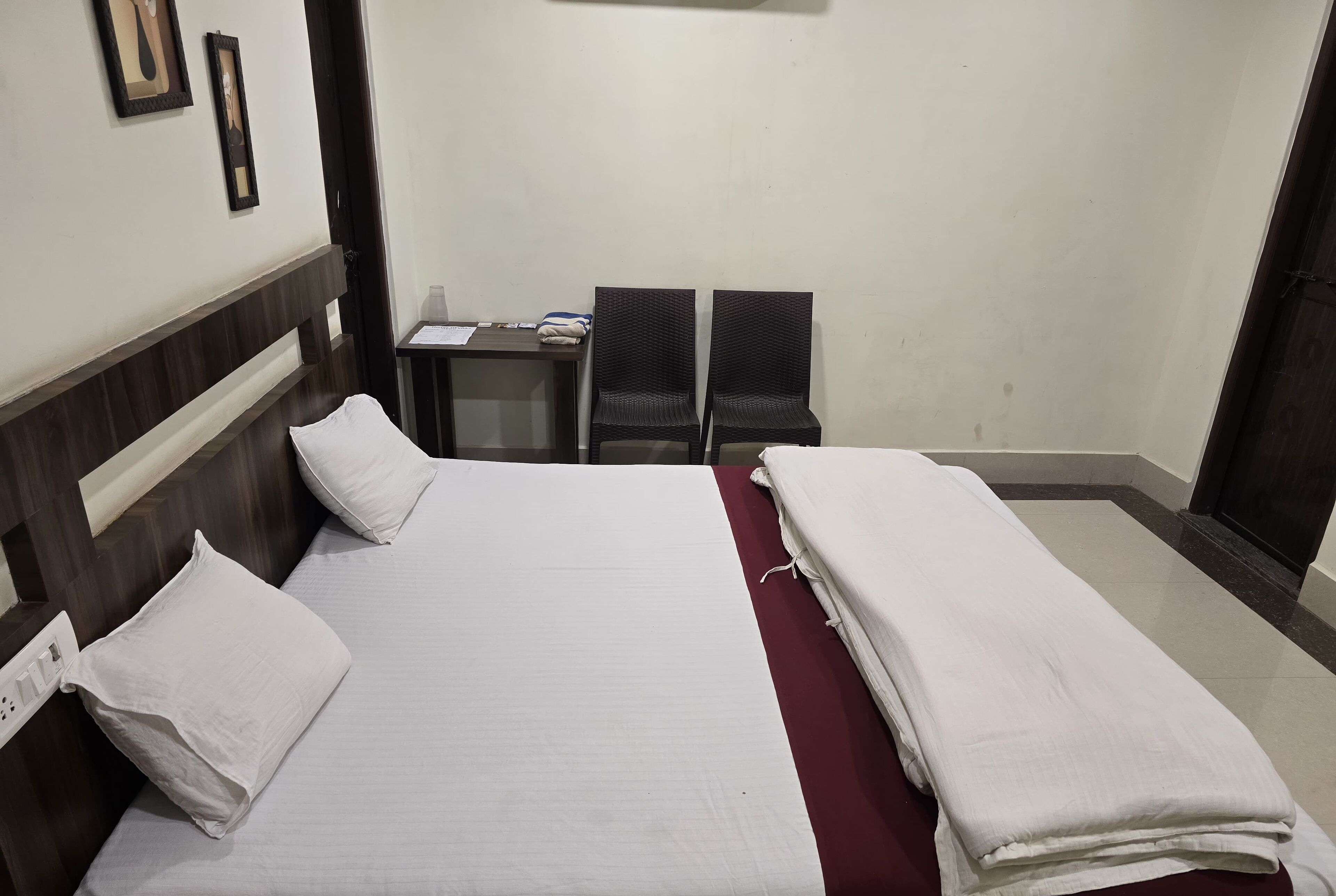 A hotel room with a bed, two chairs, a small table, and a desk.