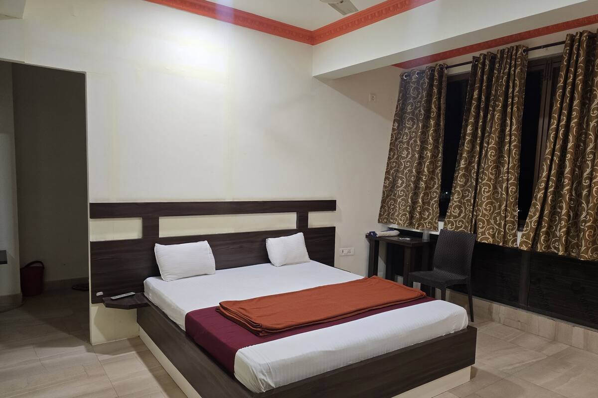 A hotel room with a bed, a desk, a chair, and curtains.