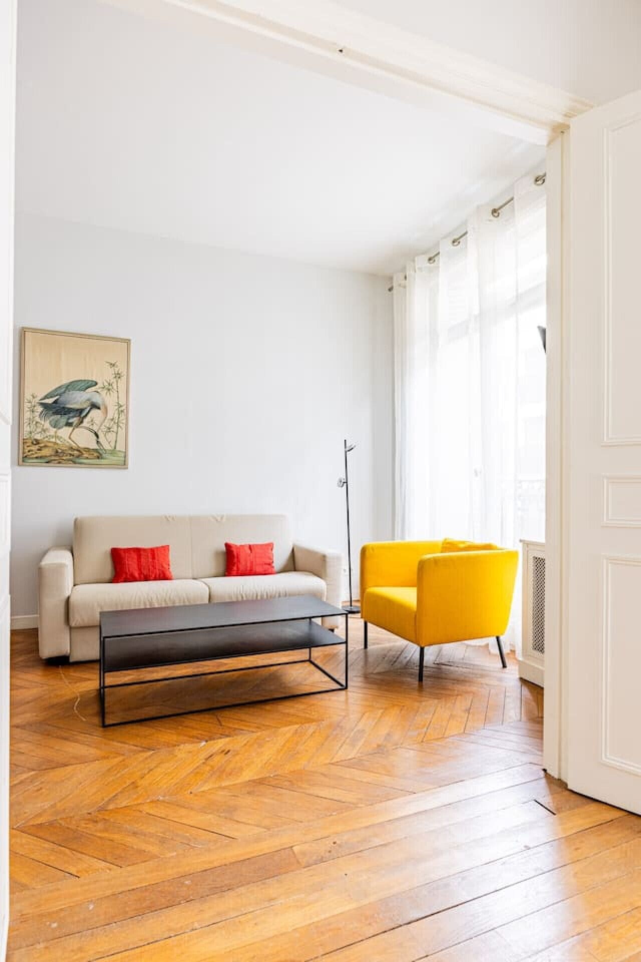Ein Wohnzimmer mit einer Couch, einem gelben Sessel, einem Couchtisch und einem Bild an der Wand.